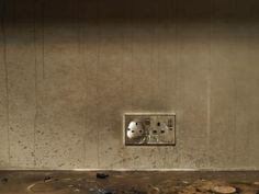 an electrical outlet on the side of a wall in a room with dirt and debris