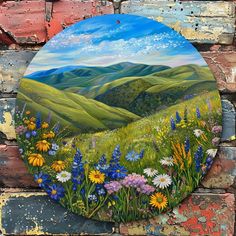 a painting on the side of a brick wall with wildflowers and mountains in the background