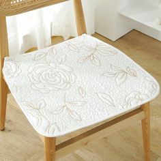 a wooden chair with a white quilted seat pad on it's backrest