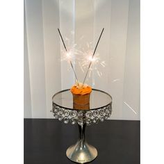 a cupcake with sparklers sitting on top of a glass table in front of a white wall