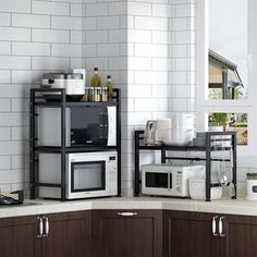 there are two microwaves on top of the shelves in this kitchen, one is silver and the other is black