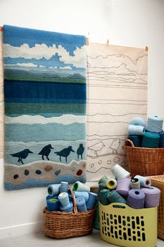 some baskets and towels are sitting on the floor in front of two wall hangings