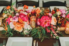 the table is set with pink and orange flowers, gold candlesticks, and plates