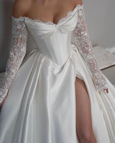 a woman in a white wedding dress with long sleeves and high slits on her legs