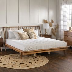 a bedroom with white walls and wooden furniture, including a bed that has pillows on it