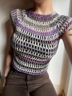 a woman with tattoos wearing a crocheted top