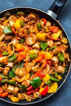 a skillet filled with chicken, peppers and pineapples on top of a blue surface