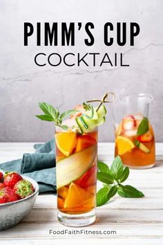 two glasses filled with fruit and minty drinks on top of a white wooden table