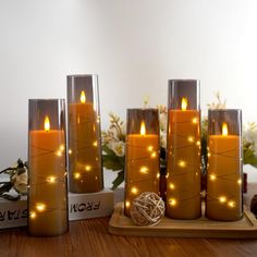 lighted candles are sitting on a wooden tray