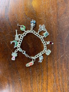 A fun vintage sterling silver charm bracelet with 11 assorted vintage charms. This bracelet is a double curb link style with a lobster claw clasp. The charms on the bracelet are a cat with a bow, a palm tree, a guitar, a dolphin, an angel with a pink gem dress, a turtle, a butterfly, a flip-flop, a crown, a tropical drink, and another cat (missing an eye). A great starter set of whimsical charms, and plenty of room to add more!  CONDITION \\ Each charm is stamped 925 and the clasp of the bracele Whimsical Silver Charms For Gifts, Vintage Charm Costume Jewelry Bracelet, Whimsical Silver Dangle Charm Necklaces, Whimsical Silver Dangling Charms, Vintage Charm Bracelet With Removable Charms, Vintage Charm Bracelet With Removable Charms As Gift, Silver Charm Bracelet With Vintage Charm As A Gift, Themed Sterling Silver Charms, Silver Vintage Charm Bracelet Gift