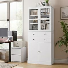 an office with a desk, chair and bookcase next to a plant in the corner