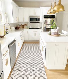 a kitchen with white cabinets and black and white floor tiles on the floor, along with gold pendant lights