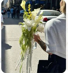 a woman holding a bouquet of flowers on the street