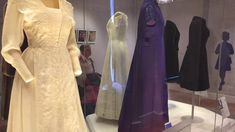 dresses are on display in a glass case