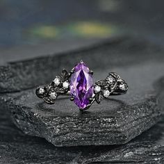 a ring with an amethorate and white diamonds on top of a rock