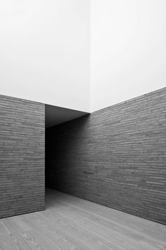 black and white photograph of an empty room with brick walls, wood flooring and wooden floors