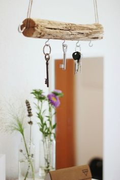 there is a piece of driftwood hanging from the ceiling with keys attached to it