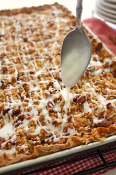 a spoon is being drizzled with icing on top of a casserole