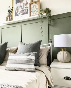 a bedroom with green walls, white bedding and two framed pictures on the wall