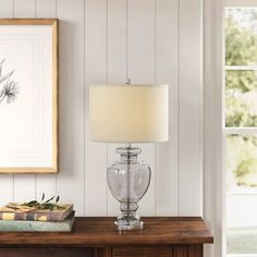 a table with a lamp on it next to a painting and a framed picture above it