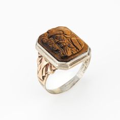 This is part of Chairish’s Fine Jewelry assortment.  Finely detailed vintage Art Deco era tigers eye cameo ring crafted in 10 karat white & yellow gold (circa 1920s to 1930s).   Tigers eye measures 16mm x 12mm. The tiger's eye is in good condition (few very minor chips visible under a 10x loupe).   The tigers eye cameo depicts the side profile of two Centurions. The tiger's eye is luminous with warm golden hues visible with every movement of the ring. The square mount has a low profile and rises Vintage Carved Signet Ring For Formal Occasions, Antique Brown Rings For Anniversary, Antique Carved Collectible Ring, Vintage Brown Ring With Polished Finish, Victorian Brown Collectible Jewelry, Victorian Style Brown Collectible Jewelry, Art Nouveau Engraved Rings Collectible, Art Nouveau Engraved Collectible Rings, Antique Intaglio Signet Ring Collectible