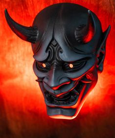 a black mask with red eyes and horns on it's face is lit up