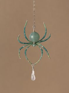 a green spider hanging from a chain on a brown wall with a white light bulb