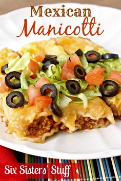 mexican manicotti with black olives, tomatoes and lettuce on a white plate