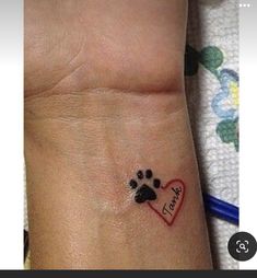 a dog paw and heart tattoo on the wrist