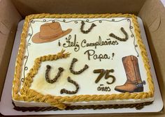 a sheet cake decorated with cowboy boots and other items is in a box on the table