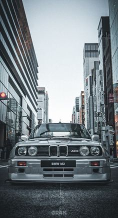 a silver car parked in front of tall buildings