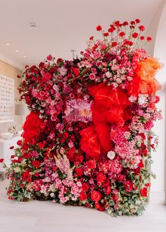 a large display of red and pink flowers in a room with white walls on either side