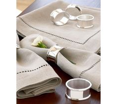 the napkins are folded on top of each other with silver rings sitting next to them