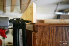 a person using a power drill to attach a piece of wood on top of a cabinet