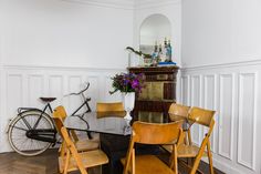 a dining room table with chairs and a bike in the corner next to it on top of a hard wood floor