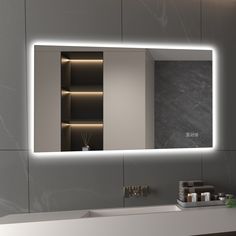 a bathroom with a large mirror and lights on the wall above it, next to a sink