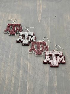 Howdy!  This listing is for a single pair of Texas A&M Glitter Acrylic Dangle Earrings.   Four options available -  - Maroon back with a Silver top layer - Maroon back with a White Glittery top layer - White Glitter back with Maroon top layer - Silver back with a Maroon top layer Wear these Texas A&M earrings at College Station football games, school events, reunions and everyday fun!    Makes a great gift for that Aggie in your life - works for birthdays, Mother's Day, Christmas or anytime. All White Glitter Jewelry For Gifts, White Glitter Jewelry Gift, White Glitter Jewelry As Gift, Glittery Top, Ring Day, Maroon Top, Pride Jewellery, Texas Gifts, Daughter Christmas