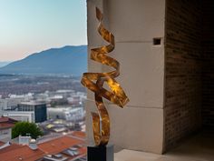 a metal sculpture on top of a building next to a tall building with mountains in the background