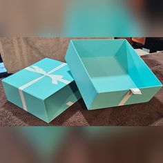 two blue boxes sitting on top of a brown carpeted floor next to each other