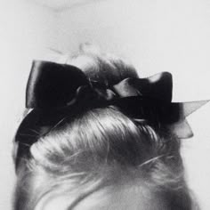 a black and white photo of a woman's head with a bow in her hair