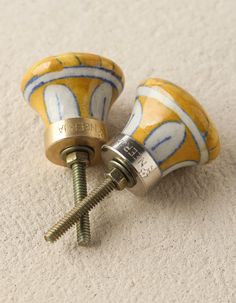 two yellow and white ceramic knobs with screws