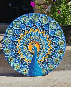 a blue and yellow peacock umbrella sitting on the ground