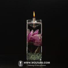 a candle that is inside of a glass vase with water and flowers on the side