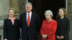 four people standing next to each other in front of a building with two women and one man