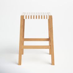 a wooden stool with a woven seat pad on the back and sides, against a white background