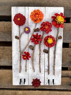 the flowers are made out of sticks and yarn on top of white wood planks