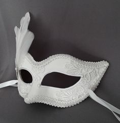 Handmade Venetian style masquerade mask in white. Eye details and edges are outlined with braided trim, front surface is partially covered with pearly off white lace. Decorated with metal rosette and feathers. Back surface is also covered with fabric for comfort. Your order will be delivered with online tracking by UPS or FedEx. Ribbons are added both sides to tie. Base mask is made of paper mache. Standard size fits most (for women). This classical Venetian mask is perfect for any costume or Ha White Formal Masquerade Mask For Carnival, White Fantasy Eye Mask, White Masquerade Mask For Halloween, Venetian White Masquerade Mask For Halloween, White Venetian Masquerade Mask For Halloween, White Eye Mask For Costume Party, White Venetian Masks And Prosthetics For Theater, Venetian White Mask For Theater, White Venetian Masks For Theater