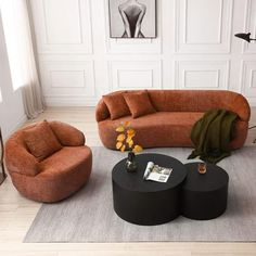 a living room with orange couches and black tables on the floor in front of a white wall