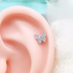 a pair of diamond earrings sitting on top of a pink ear