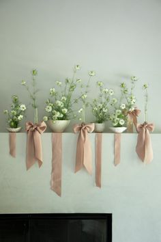 three vases filled with flowers on top of a mantel above a fire place